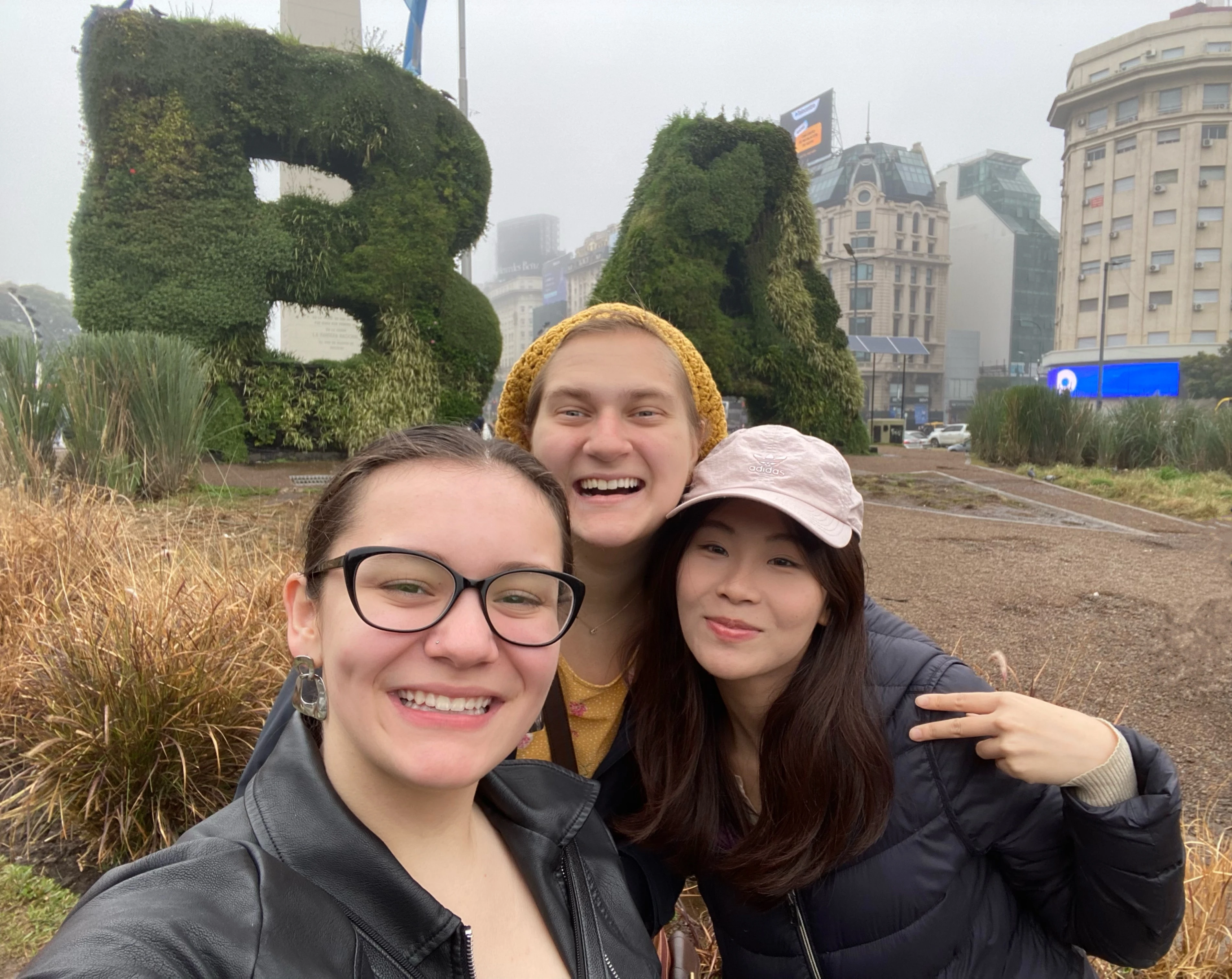 Carmen with two close friends that she met during Buenos Aires, standing near a city’s sign in downtown, with the famous monument El Obelisco in the background 